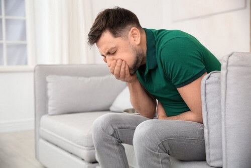 Ragazzo seduto sul divano con la nausea. 