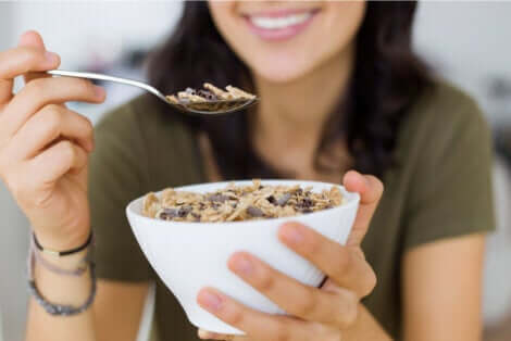 Ragazza che aggiunge i semi ai cereali per la colazione.