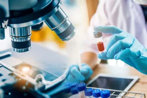 Tecnico di laboratorio con microscopio e provette.