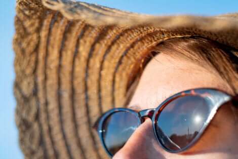 Viso femminile con occhiali da sole e cappello di paglia.