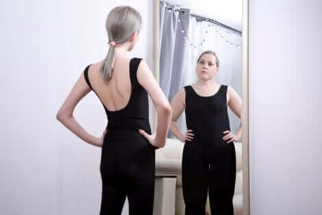 Adolescente magra allo specchio vede la propria immagine obesa.