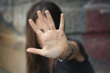 Ragazza si copre il volto con la mano tesa.