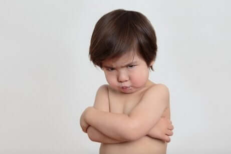 Bambino imbronciato a braccia incrociate.