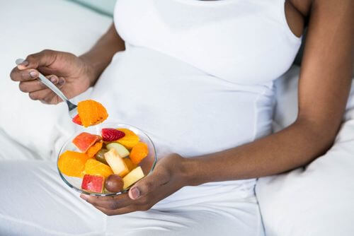 Donna che mangia frutta in gravidanza.