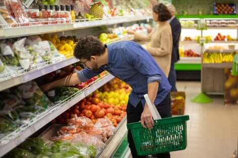 Uomo sceglie la sicurezza alimentare e la verdura al supermercato.