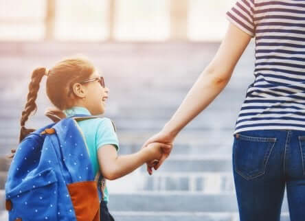 Bambina che va a scuola accompagnata da un adulto.