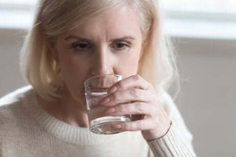 Donna che beve per ridurre la caduta dei capelli in menopausa.