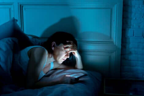 Donna con insonnia utilizza il cellulare.