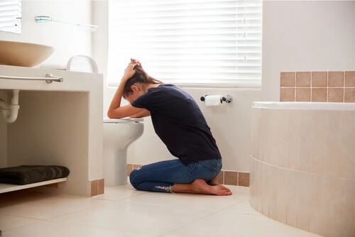 Donna che vomita in bagno.
