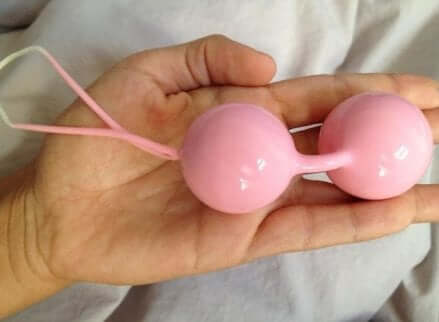 Mano con palline cinesi rosa.