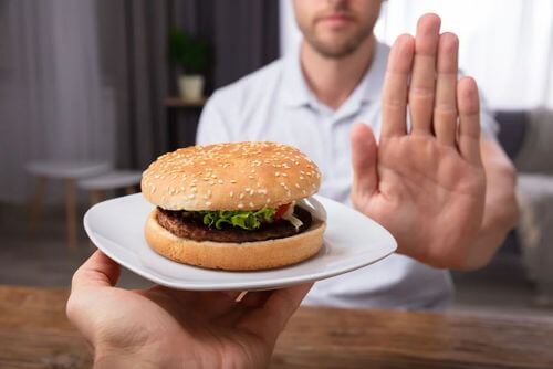 Uomo che rifiuta del cibo che rientra tra le cause di bruciore di stomaco.