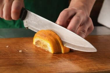 Eliminare l'odore di pesce: uomo che taglia un'arancia a fette.