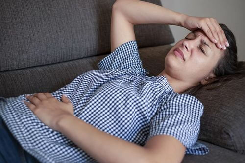 Donna sdraiata con nausea.