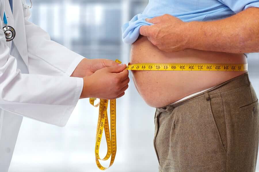 Medico misura addome di paziente obeso.