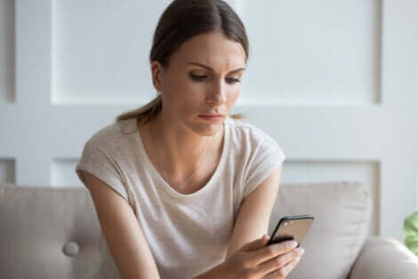 Donna che guarda il cellulare perché continua a pensare allo ex.