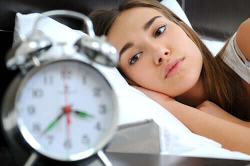 Ragazza a letto che guarda la sveglia.