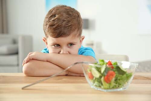 Bambino che rifiuta di mangiare l'insalata.