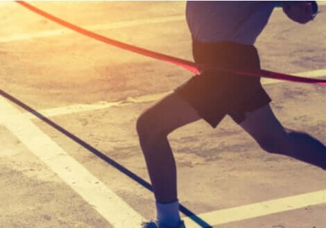 Maratona: corridore che taglia il traguardo.