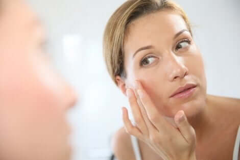 Donna che si applica una crema sul viso per contrastare il fotoinvecchiamento.