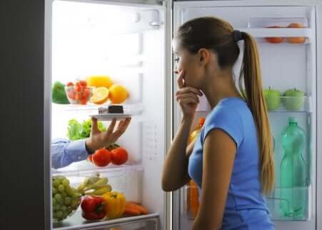 Donna guarda dentro al frigorifero. 