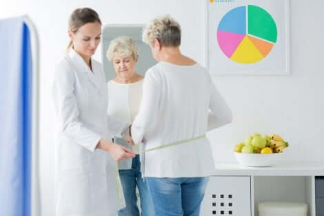 Cambiamenti del corpo durante la menopausa: medico che misura la vita di una donna.