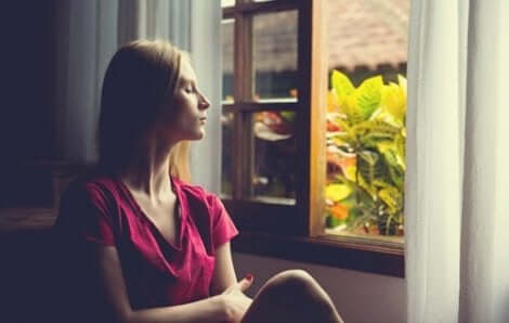 Donna con occhi chiusi seduta alla finestra.