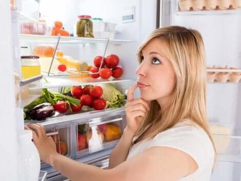 Ragazza davanti al frigo aperto pensa a cosa mangiare.