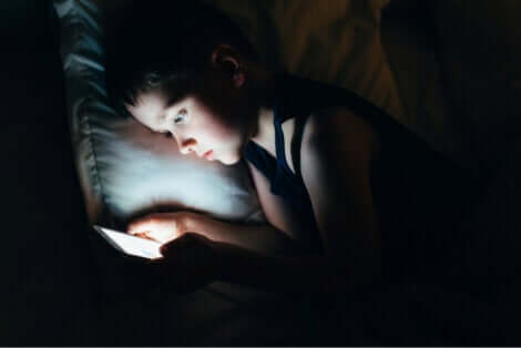 Social network e bambino che usa un tablet a letto.