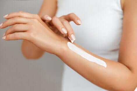 Donna applica crema solare sul braccio.