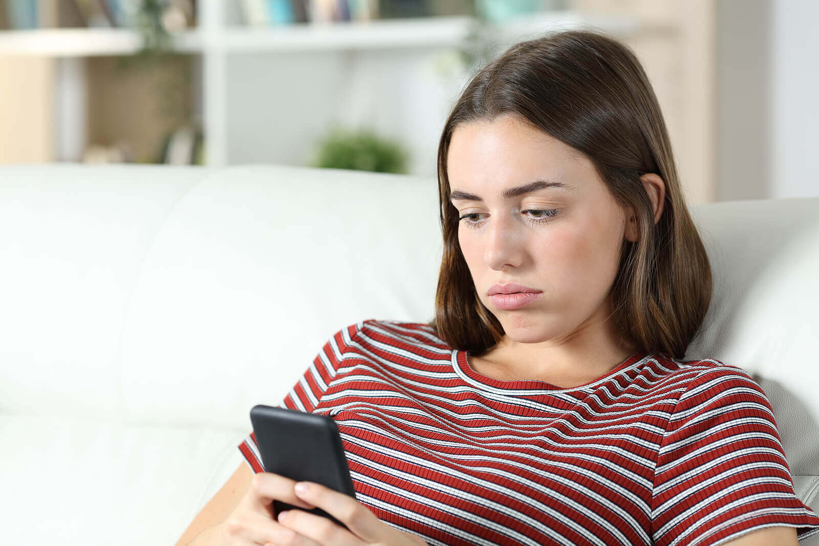 Donna annoiata con il cellulare.
