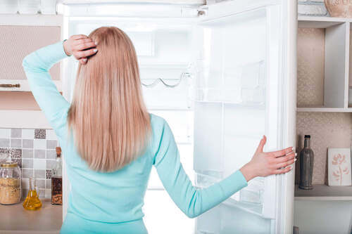 Donna che apre il frigorifero.