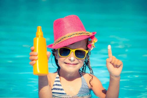 Bambina con crema solare e occhiali da sole.