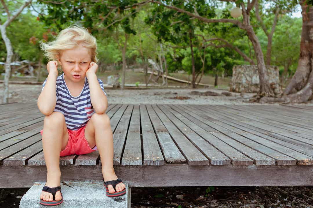 Bambino capriccioso seduto a terra.