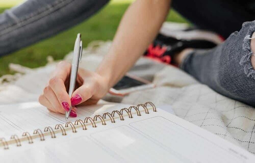 Donna che scrive su un quaderno ad anelli.