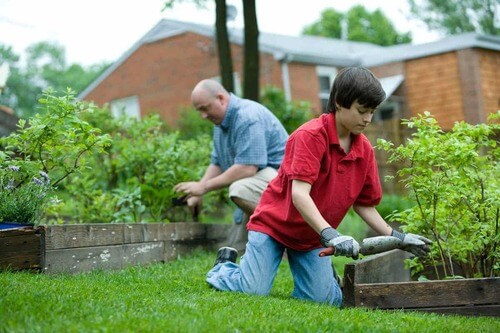 Nipote e nonno che fanno giardinaggio per prevenire le malattie più comuni nella vecchiaia.
