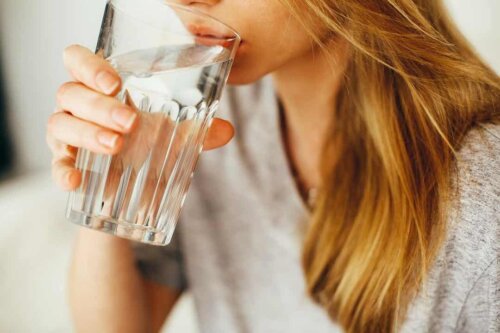 Donna che beve un bicchiere d'acqua.