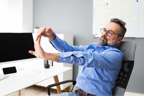 Uomo che fa stretching davanti il computer per affrontare al meglio la vecchiaia.