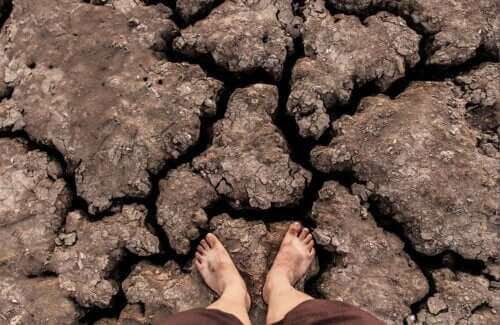 Piedi su una roccia arida e il cambiamento climatico.