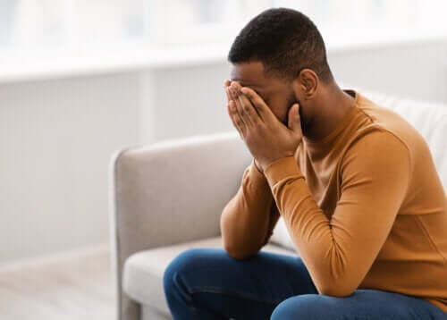 Uomo con le mani sul viso ed essere una persona negativa.