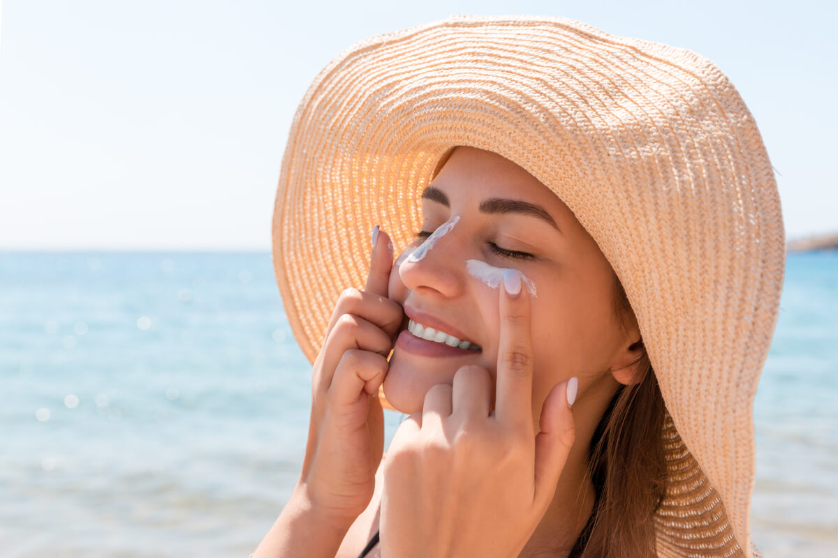 Donna applica crema solare sul viso.